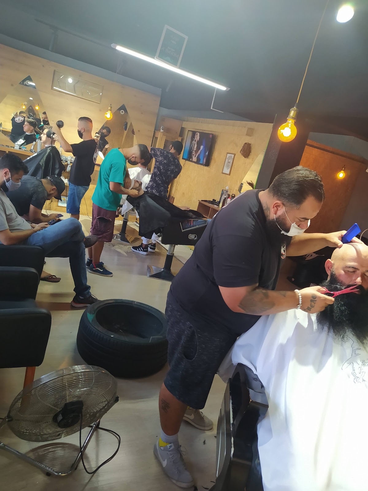 Barbeiro da Barbearia Lucão cortando cabelo e barba de um cliente